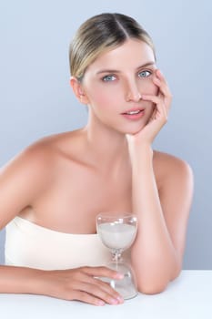 Alluring beauty model using hourglass in beauty concept of anti-aging skincare treatment for woman. Beautiful caucasian women portrait with perfect smooth clean skin in isolated background.