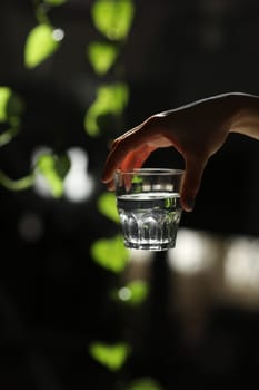 Woman holding a glass of water on a dark background. glass of pure water in hand. Healthy Lifestyle