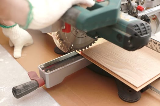 Installation laminate or parquet in the room, worker cuts a laminate of a certain length with an electric saw. self-repair of the floor in the house.