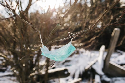 blue used mask on wood, face mask pollution of nature, Discarded coronavirus single-use face masks, Garbage in the streets threatens the environment, a mask on a tree in a park.