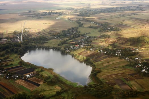 view of the village from the sky. photo with noise. Aerial view of farmland area landscape and lake from airplane. Landscape with lake. Environment protection. Drone flight