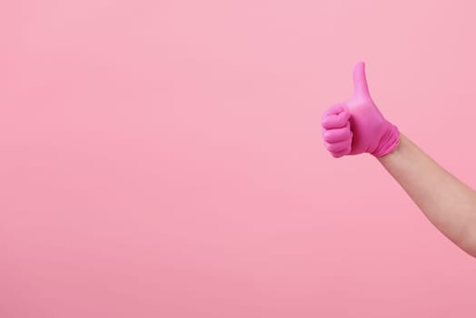 Hands of a girl in pink latex gloves on pink background. Virus protection, medical sterility