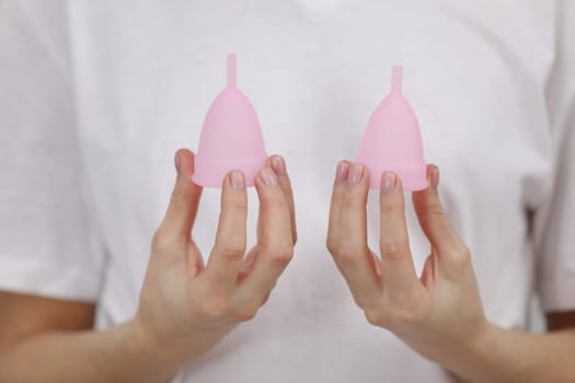 Close up of woman hand holding differently sized menstrual cups. Women health concept, zero waste alternatives.