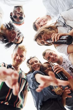 Looking down. View from below. Group of young people in casual clothes have a party at rooftop together at daytime.