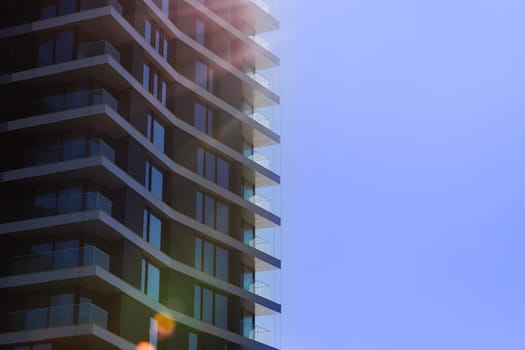 Fragment of modern multi-storey residential building against blue sky. Close-up. Background for ad or banner. Copy space. modern housing. sale of apartments