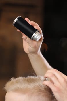 Close up of a professional barber using hair powder for styling on client's hair while working in the modern barbershop. Hairdressing. hair cutting. Creating a stylish hairstyle in a barbershop