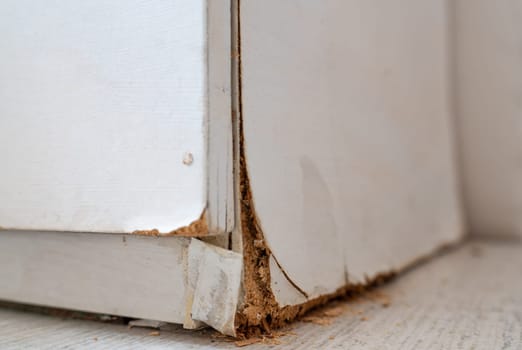 Weathered white wooden cabinet with flaking layers due to humidity.