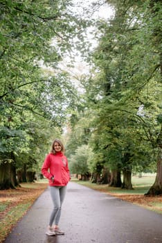 Close up portrait of a beautiful girl in the park in autumn. Close up portrait of a young caucasian woman girl with toothy smile walking in park forest outdoors looking at camera. Portrait of a cute beautiful blonde in a straw hat close-up