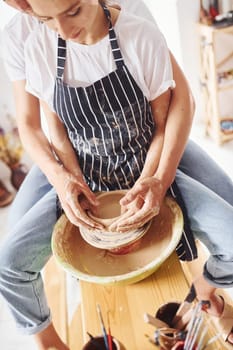 With her boyfriend or husband. Young female ceramist have a works indoors with handmade clay product. Conception of pottery.