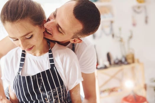 With her boyfriend or husband. Close up view of young female ceramist that indoors with handmade clay product. Conception of pottery.
