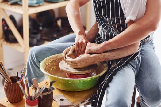 With her boyfriend or husband. Close up view of young female ceramist that indoors with handmade clay product. Conception of pottery.