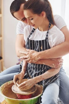 With her boyfriend or husband. Young female ceramist have a works indoors with handmade clay product. Conception of pottery.