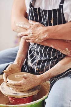 With her boyfriend or husband. Close up view of young female ceramist that indoors with handmade clay product. Conception of pottery.