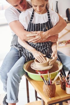 With her boyfriend or husband. Young female ceramist indoors with handmade clay product. Conception of pottery.