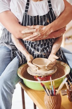 With her boyfriend or husband. Close up view of young female ceramist that indoors with handmade clay product. Conception of pottery.