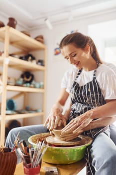 With her boyfriend or husband. Young female ceramist indoors with handmade clay product. Conception of pottery.