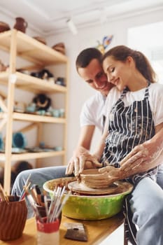 With her boyfriend or husband. Young female ceramist indoors with handmade clay product. Conception of pottery.