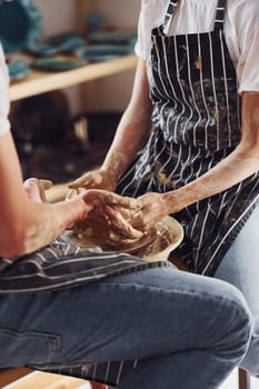 With her boyfriend or husband. Close up view of young female ceramist that indoors with handmade clay product. Conception of pottery.