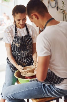 With her boyfriend or husband. Young female ceramist indoors with handmade clay product. Conception of pottery.