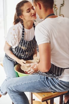 With her boyfriend or husband. Young female ceramist indoors with handmade clay product. Conception of pottery.