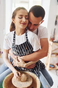 With her boyfriend or husband. Young female ceramist indoors with handmade clay product. Conception of pottery.