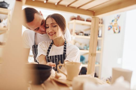 Job is done. With her boyfriend or husband. Young female ceramist indoors with finished handmade clay product. Conception of pottery.