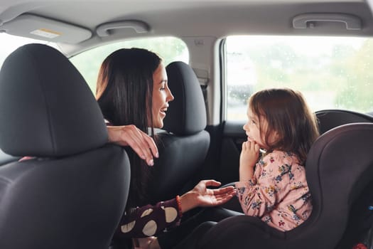 Mother with her daughter inside of modern automobile together.