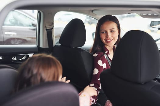 Mother with her daughter inside of modern automobile together.