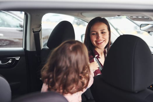 Mother with her daughter inside of modern automobile together.