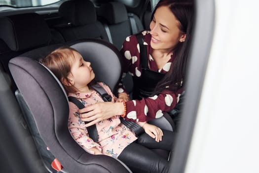 Mother with her daughter inside of modern automobile together.
