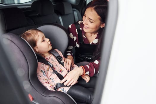 Mother with her daughter inside of modern automobile together.