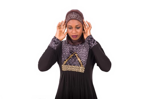 young muslim woman standing in long dress in prayer position.