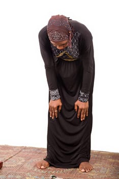 young muslim woman in long dress in prayer position.