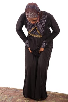 young muslim woman in long dress in prayer position.