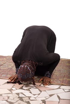 young muslim woman in long dress on mat praying.