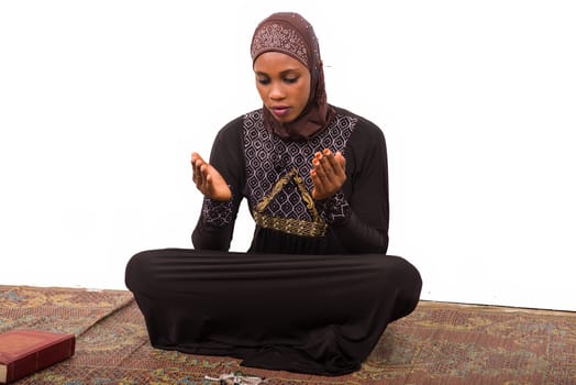 young muslim woman sitting on a mat praying.