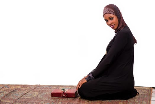 young muslim woman sitting on a mat smiling at the camera.