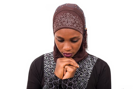 young muslim woman standing on white background praying.