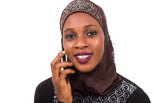 young muslim woman sitting interacting with mobile phone while smiling.