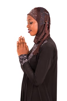 young muslim woman isolated on white background praying while smiling.