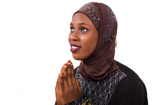 young muslim woman isolated on white background praying while smiling.