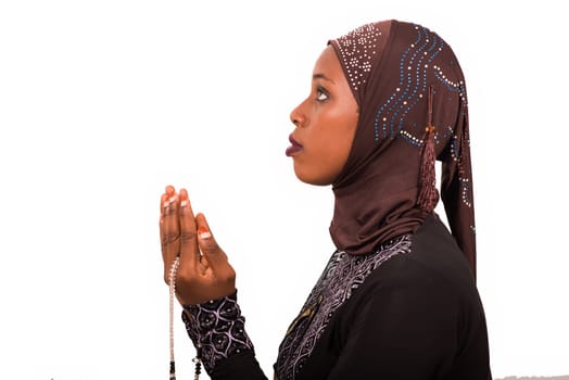 young muslim woman sitting on a mat praying.
