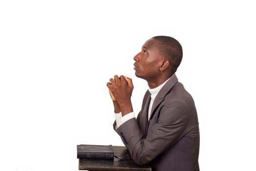 portrait of young pastor kneeling and praying head up.