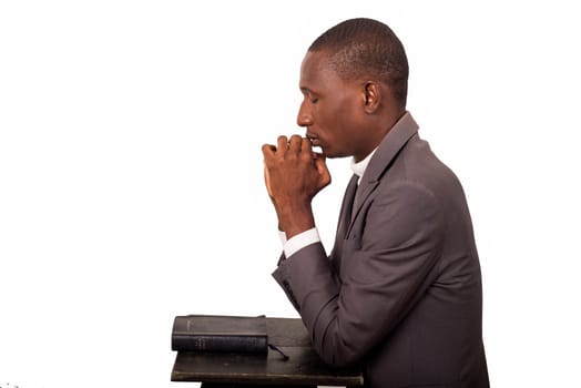 portrait of young pastor kneeling and praying with head down.