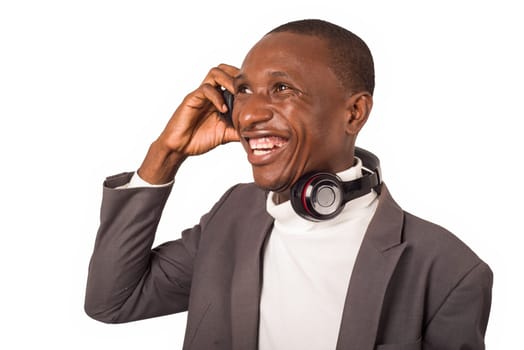 portrait of young man in suit standing and listening to music while smiling isolated on white background.