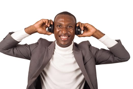 portrait of young man in suit standing and listening to music with headphones while smiling isolated on white background.