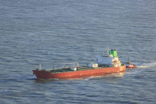 Cargo Ship and Tugboat Navigate Calm Ocean Waters Entering Port. High quality photo