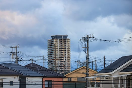 High rise apartment tower over electrical wires and suburban houses. High quality photo