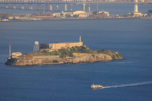 Alcatraz Island and sightseeing ferry in San Francisco Bay at Golden Hour. High quality photo