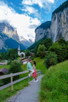 men and women visiting Lauterbrunnen valley with a gorgeous waterfall and Swiss Alps in the background, Berner Oberland, Switzerland, Europe during summer